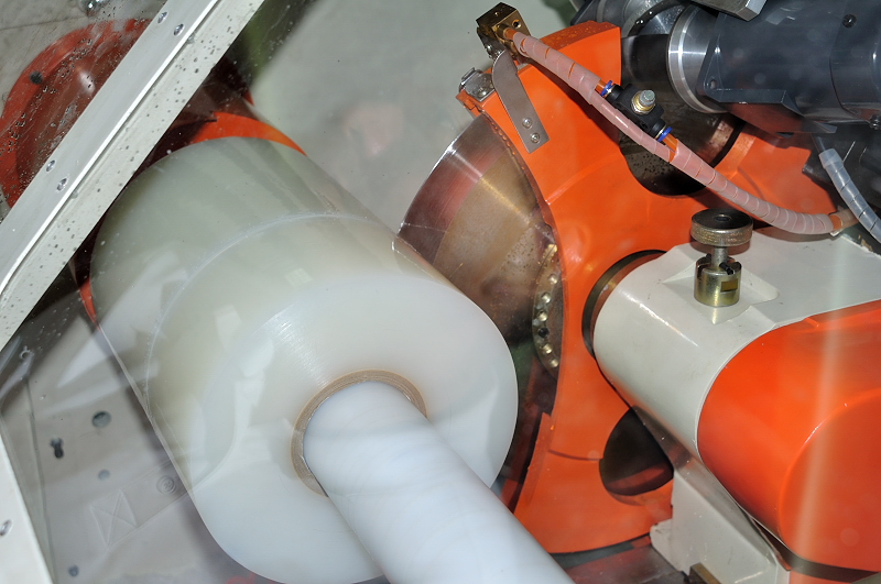 Close-up of a log roll being cut by a rotary blade inside the cutting chamber